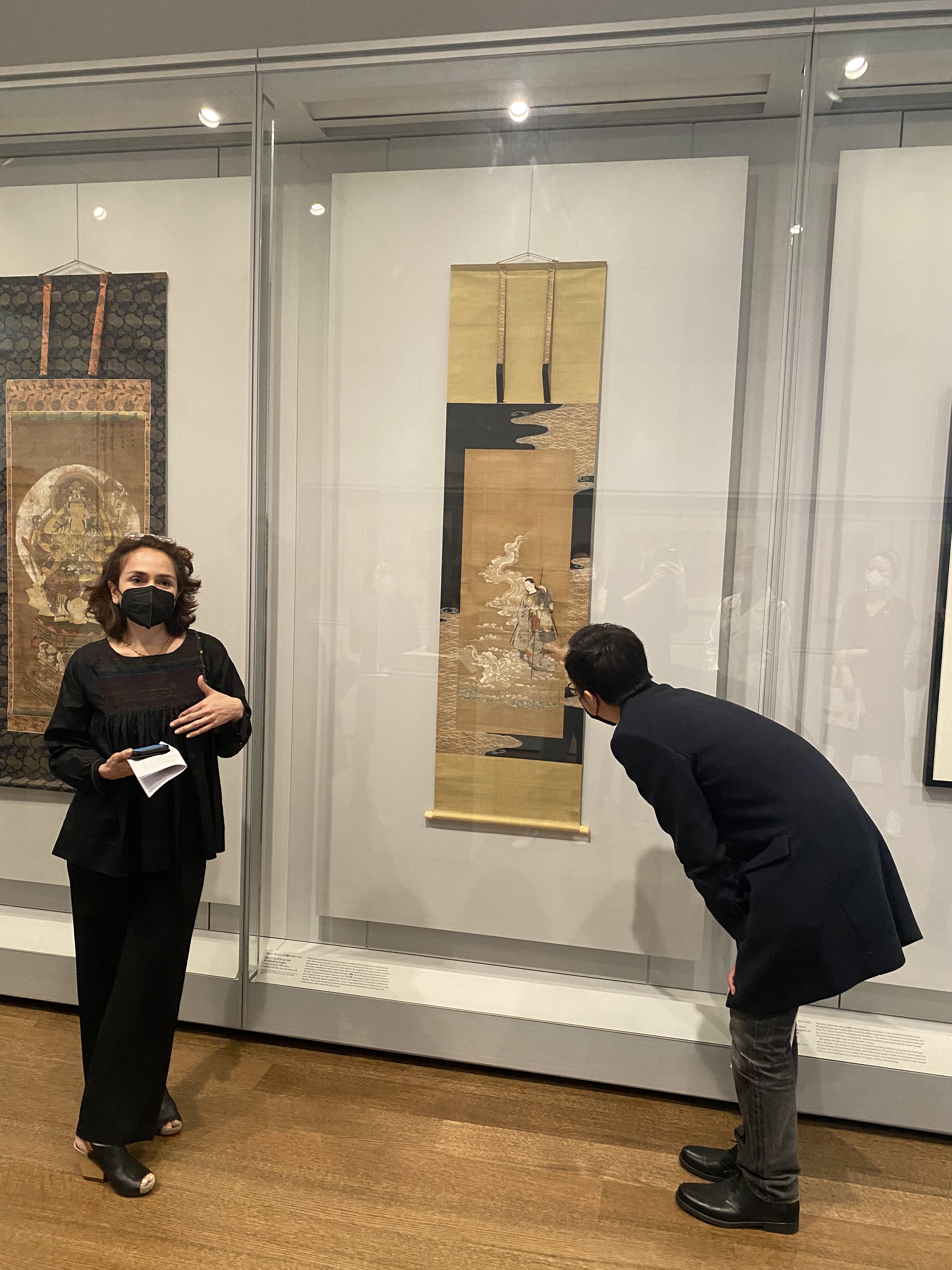 Professor introduces a painting while student looks closely